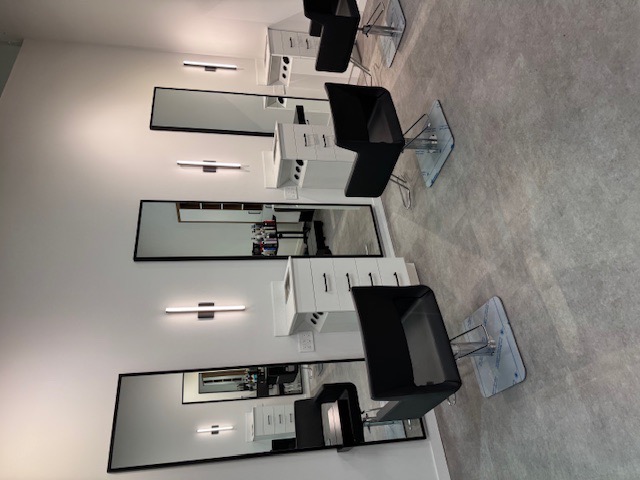 Finished salon stations with chairs, mirrors, and sconce lighting